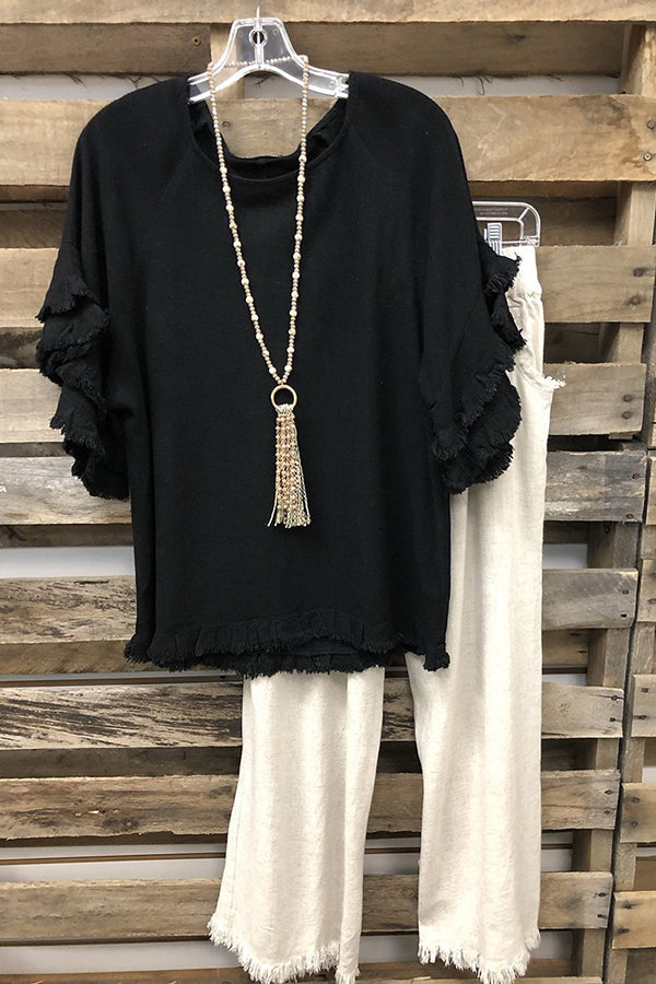 Camisa lisa negra con cuello redondo, manga corta y volantes